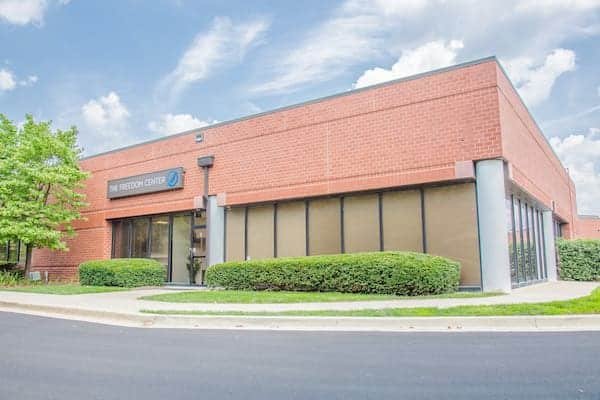 Red brick building with large windows and The Freedom Center sign under a partly cloudy sky.