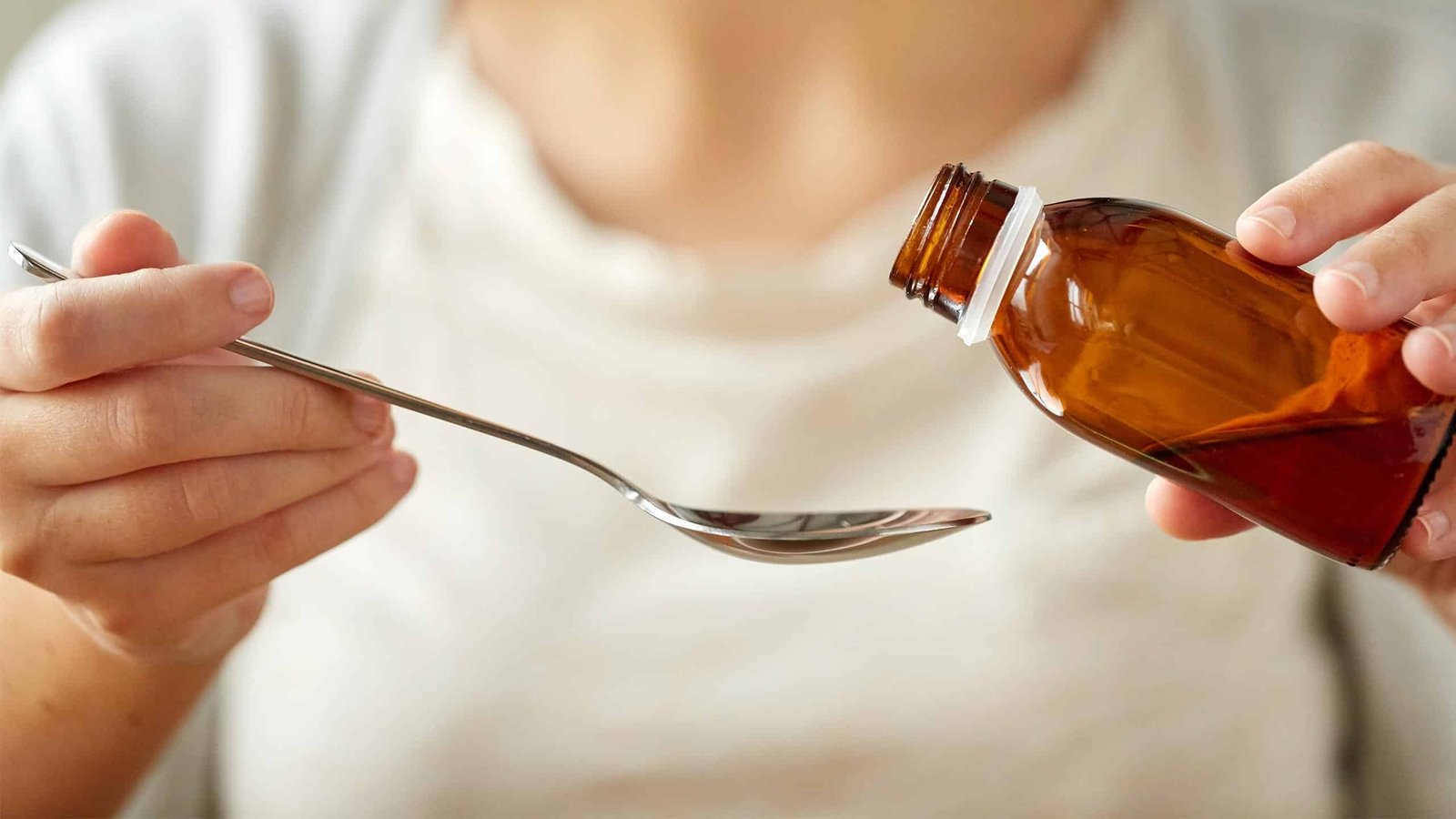 Stilpane Syrup: A woman pouring a liquid from a medicinal bottle into a spoon.