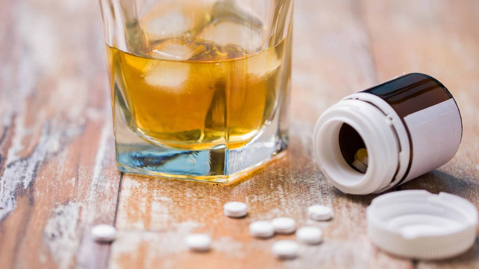 What Is Laudanum: Pills and alcohol on a wooden surface.